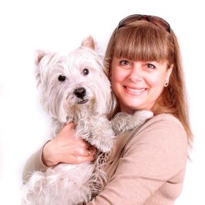 Mujer sosteniendo un perro blanco.